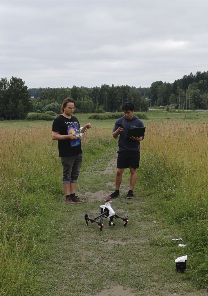 Two WeatherSens engineers preparing a sensor drone on a field track, laptop in hand.